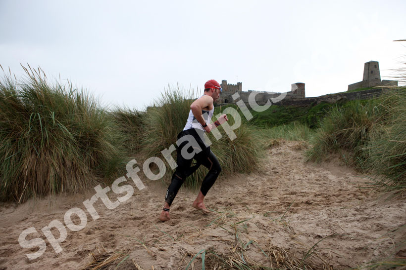 In transition from swimming to cycle during the Bamburgh Triathlon with Bamburgh Castle as a backdrop as the rain starts